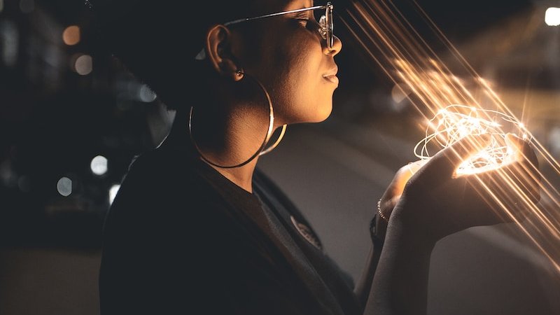 woman standing and holding string lights