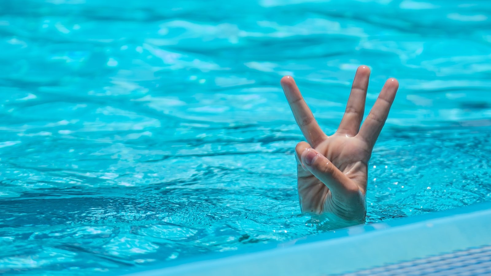 a person making a peace sign in a pool