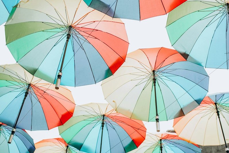 pink umbrellas hanging on white string during daytime