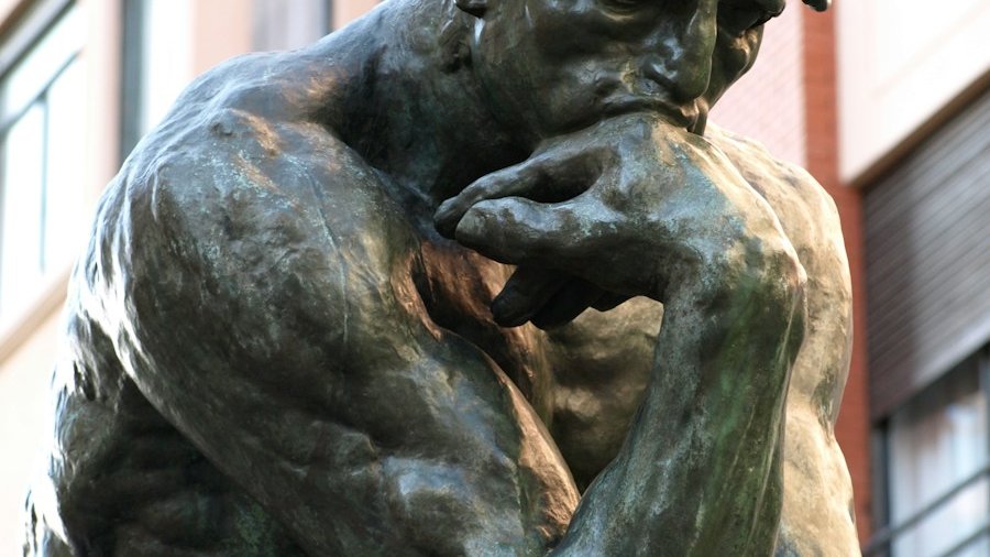 a bronze statue of a man with his hand on his face