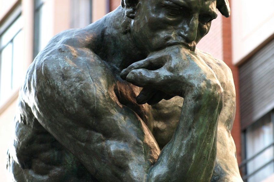 a bronze statue of a man with his hand on his face