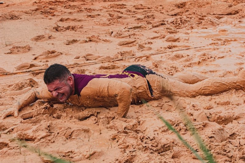 boy in red and blue shirt lying on brown sand during daytime
