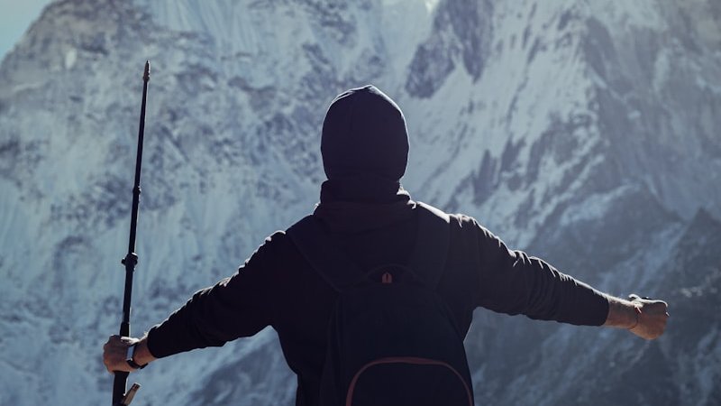 a man holding a rifle while standing on top of a mountain