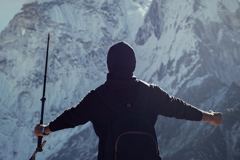a man holding a rifle while standing on top of a mountain
