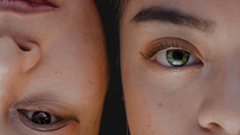 Pensive adult ethnic mother and daughter lying cheek to cheek