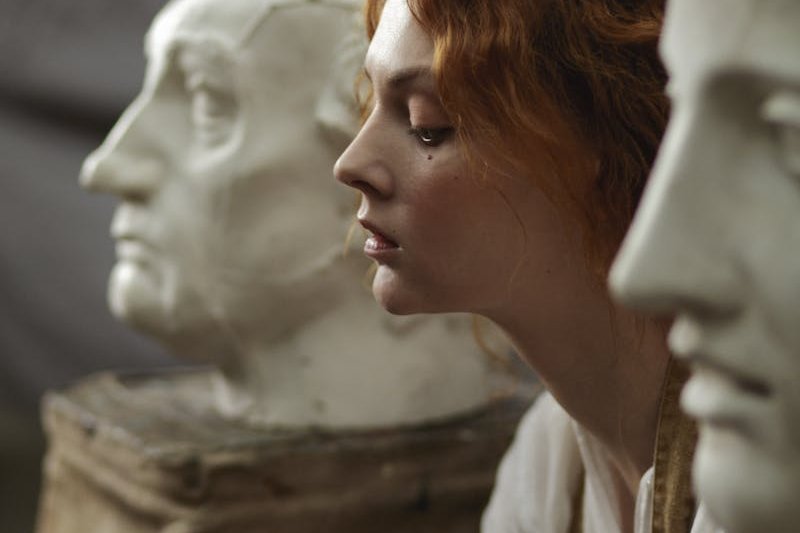 Photo of a Woman Sitting Beside Statue