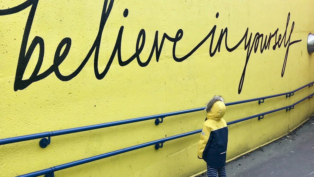 toddler looking at believe in yourself graffiti