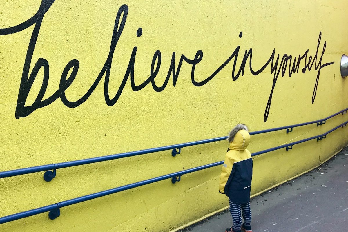 toddler looking at believe in yourself graffiti