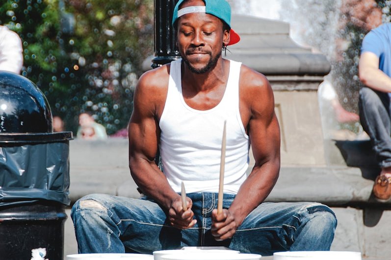 man in white tank top playing with three white plastic buckets
