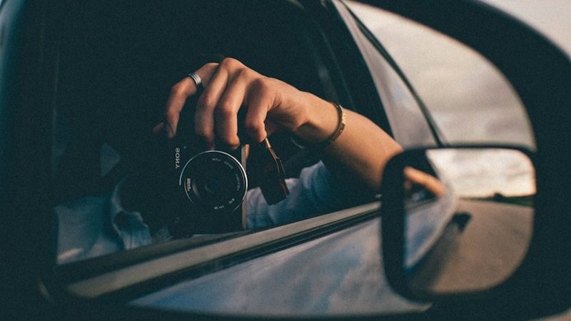 person using camera at the side mirror