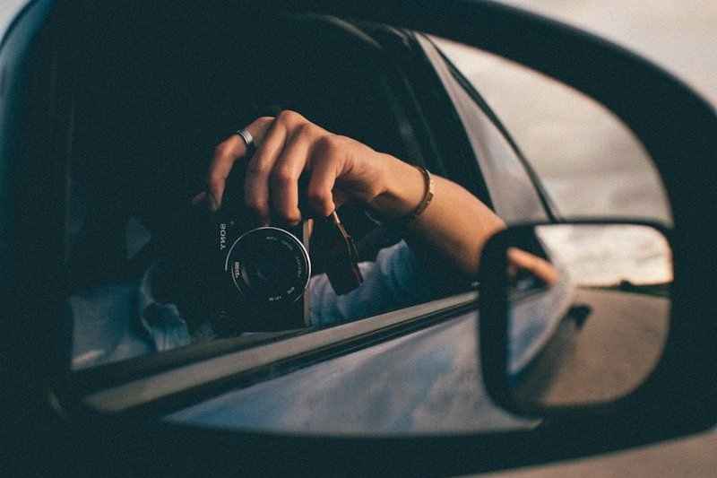 person using camera at the side mirror