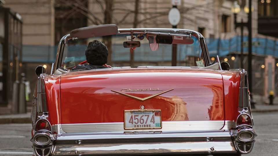 a red convertible car driving down a city street